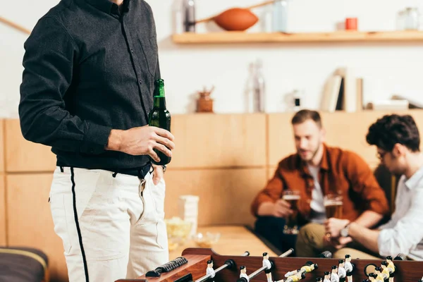 Частковий вид чоловіка з пивом і друзями позаду на дивані в кафе — стокове фото