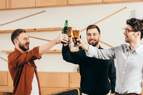 Smiling young friends clinking drinks in cafe — Stock Photo