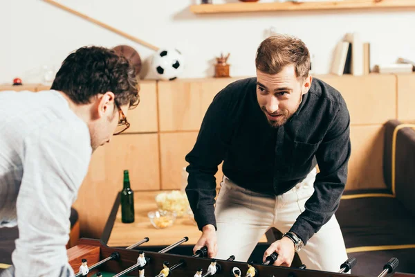 Young friends playing table soccer in cafe — Stock Photo