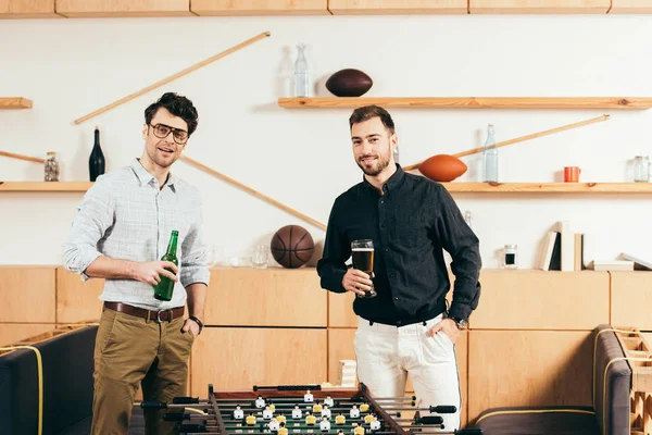 Portrait of young men with beer standing at table soccer in cafe — Stock Photo