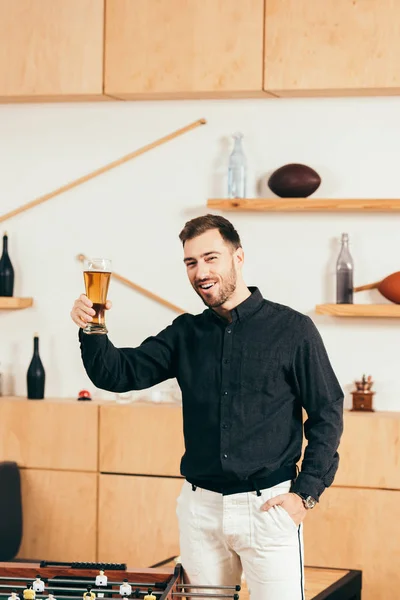 Hombre feliz con un vaso de cerveza mirando a la cámara en el café - foto de stock