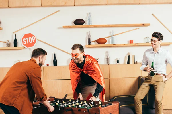 Молодые веселые друзья играют вместе в настольный футбол в кафе — стоковое фото