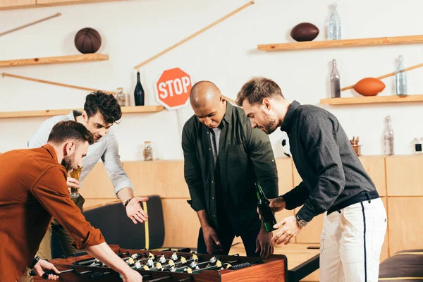 Multiracial young friends playing table football together in cafe — Stock Photo