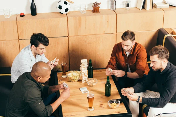 Мультикультурні чоловіки грають у карти, проводячи час разом у кафе — стокове фото