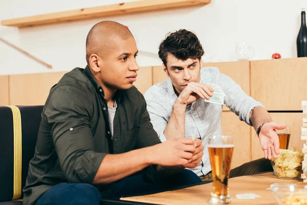 Hombres multiculturales jugando a las cartas mientras pasan tiempo juntos en la cafetería - foto de stock