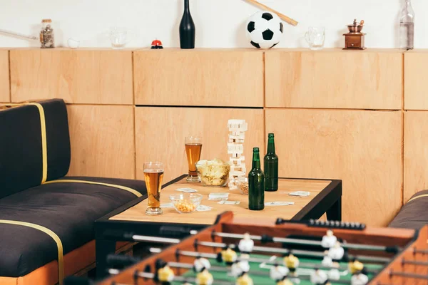 Vista de cerca de la cerveza, aperitivos y bloques juego de madera en la mesa en la cafetería - foto de stock