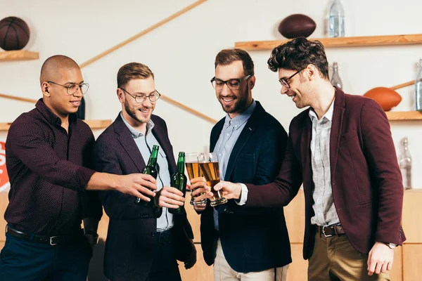 Sonriente equipo de negocios multirracial tintineando bebidas mientras descansan juntos en la cafetería - foto de stock