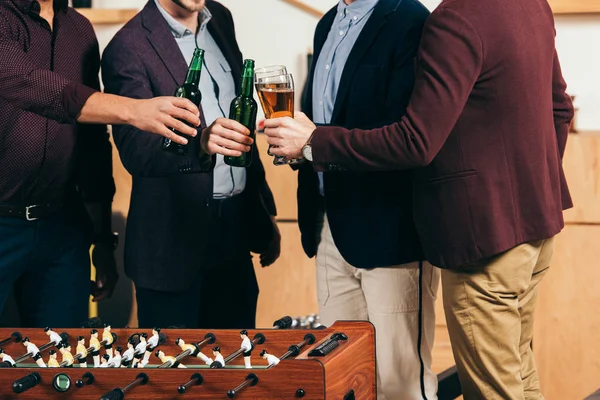 Partial view of businessmen clinking drinks at table soccer in cafe — Stock Photo