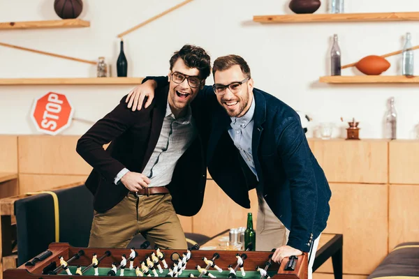 Портрет усміхнених бізнесменів з пивом, що стоїть за столом футболу в кафе — стокове фото