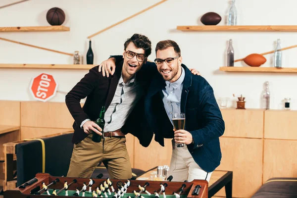 Ritratto di uomini d'affari sorridenti con birra in piedi a calcio balilla in caffè — Foto stock