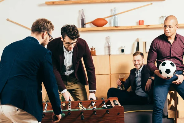 Hombres de negocios multirraciales jugando al futbolín mientras descansan en la cafetería - foto de stock