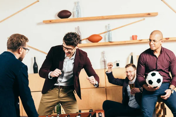 Multirassische Geschäftsleute spielen Tischfußball, während sie sich im Café ausruhen — Stockfoto