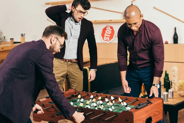 Multirassische Geschäftsleute spielen Tischfußball, während sie sich im Café ausruhen — Stockfoto