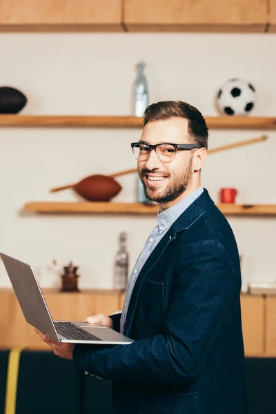 Вид сбоку улыбающегося бизнесмена с ноутбуком в кафе — стоковое фото