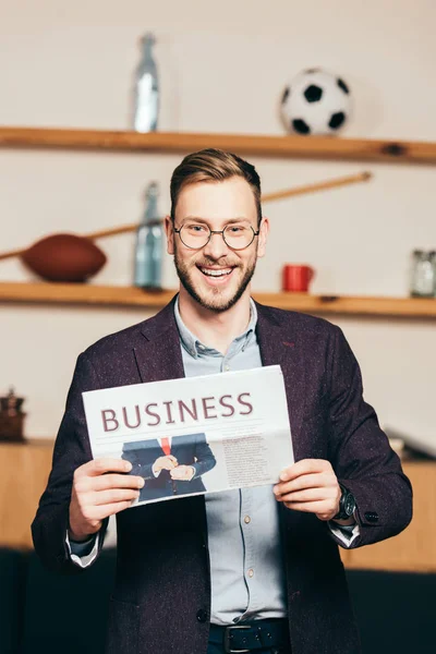 Portrait of cheerful businessman showing newspaper in hands in cafe — Stock Photo