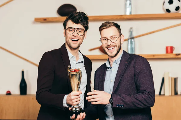 Portrait of smiling businessmen with champions goblet in cafe — Stock Photo