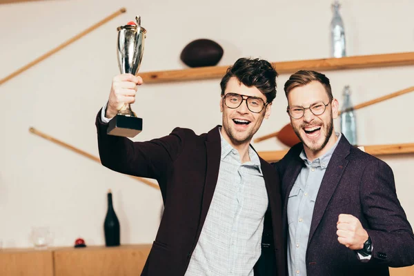 Portrait of happy businessmen with champions goblet in cafe — Stock Photo