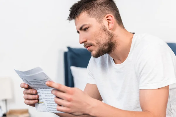 Schöner ernsthafter Mann liest morgens zu Hause Zeitung im Bett — Stockfoto