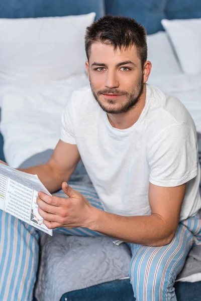 Blick aus der Vogelperspektive auf einen gutaussehenden Mann, der morgens zu Hause Zeitung im Bett hält — Stockfoto