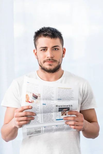 Bell'uomo che tiene il giornale e guarda la macchina fotografica al mattino a casa — Foto stock