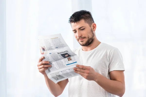 Bell'uomo che legge il giornale aziendale in camera da letto al mattino a casa — Foto stock