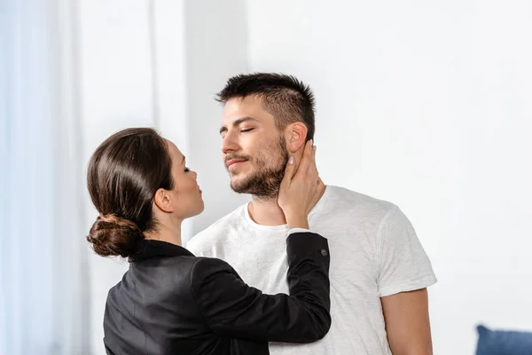 Girlfriend in suit going to kiss boyfriend in pajamas in bedroom in morning at weekday, gender equality concept — Stock Photo