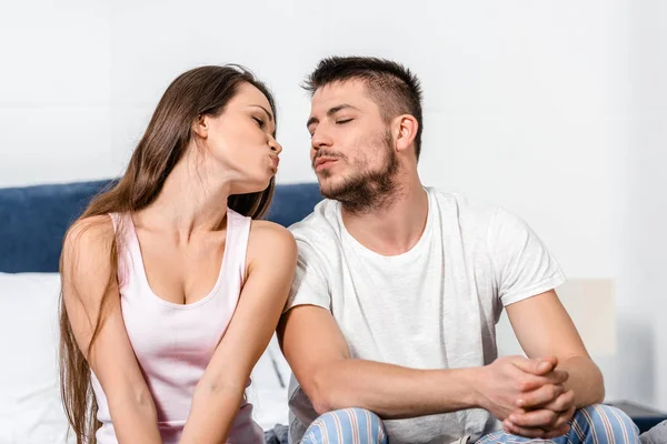 Petite amie et petit ami en pyjama va embrasser sur le lit dans la chambre — Photo de stock