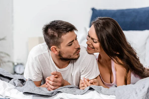 Girlfriend and boyfriend in pajamas lying on bed and going to kiss in bedroom — Stock Photo