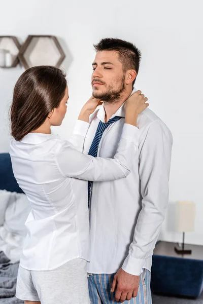 Girlfriend fixing boyfriend shirt in morning in bedroom, social role concept — Stock Photo