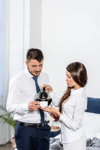 Petite amie verser du café dans la tasse copain le matin à la maison, concept de rôle social — Photo de stock