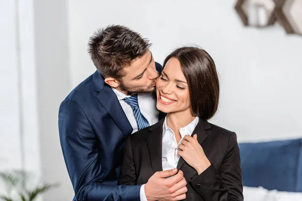 Handsome boyfriend kissing smiling attractive girlfriend before work at home — Stock Photo