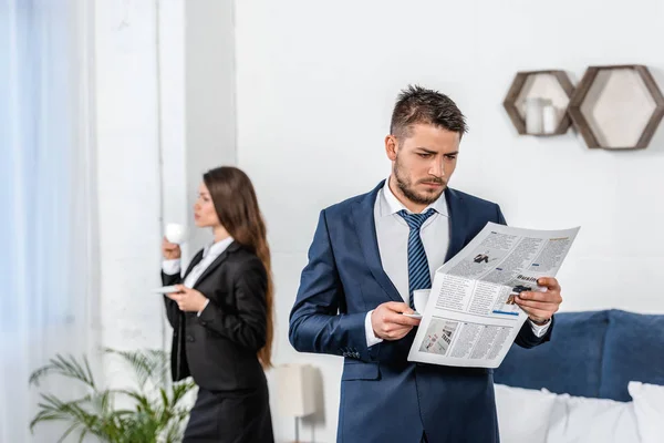 Girlfriend drinking coffee and boyfriend reading newspaper in morning at home — Stock Photo