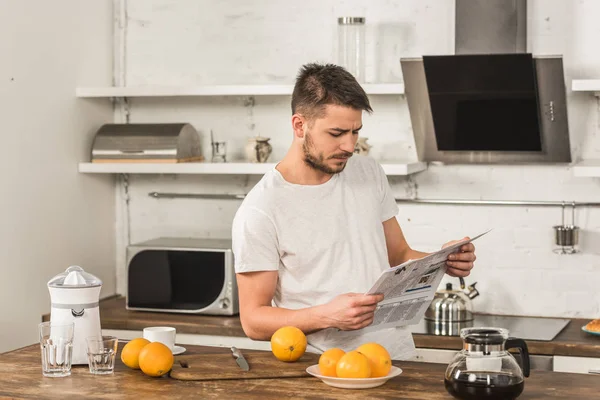 Hombre guapo leyendo el periódico en la mañana en la cocina - foto de stock