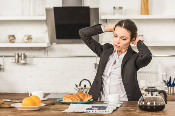 Attractive woman in shirt and jacket making ponytail in morning at kitchen — Stock Photo