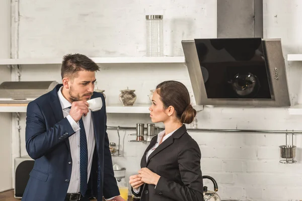 Novio bebiendo té y mirando a la novia en la mañana en la cocina - foto de stock