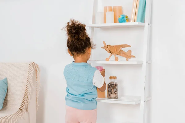 Back view of cute african american child looking at toys on shelves — Stock Photo