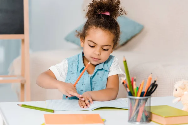 Hermoso niño afroamericano estudiando y escribiendo con lápiz - foto de stock