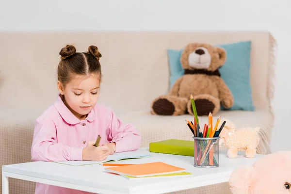 Lindo niño sosteniendo lápices y estudiando en casa — Stock Photo