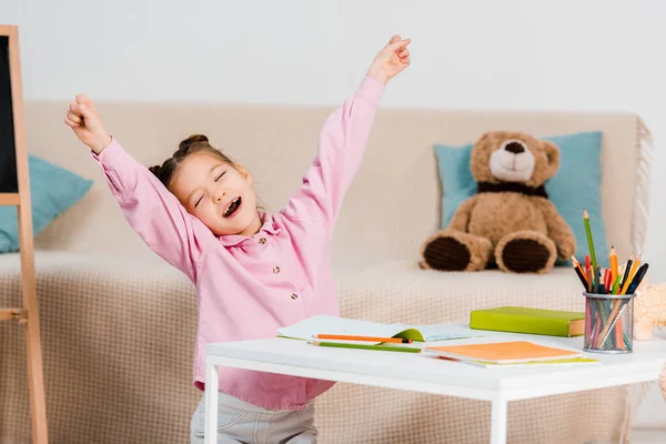 Cute child stretching and yawning while studying at home — Stock Photo