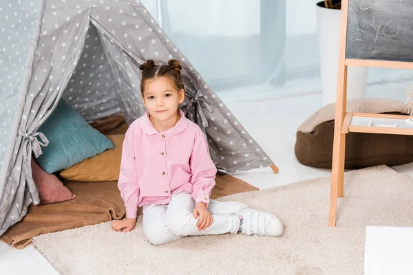 Vista ad alto angolo di adorabile bambino seduto sul tappeto e sorridente alla fotocamera — Foto stock