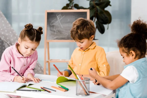 Entzückende kleine multiethnische Kinder, die zusammen zeichnen und lernen — Stockfoto