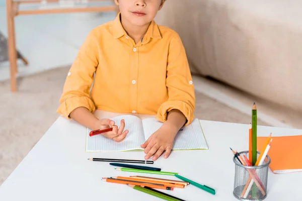 Recortado tiro de niño celebración pluma y estudiar en casa — Stock Photo
