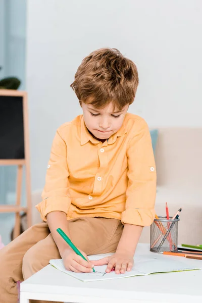 Зосереджений маленький хлопчик пише і навчається вдома — стокове фото