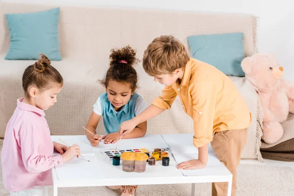 Aus der Vogelperspektive von entzückenden multiethnischen Kindern, die mit Farben und Pinseln zeichnen — Stockfoto