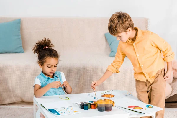 Hermosos niños multiétnicos pintando cuadros juntos - foto de stock