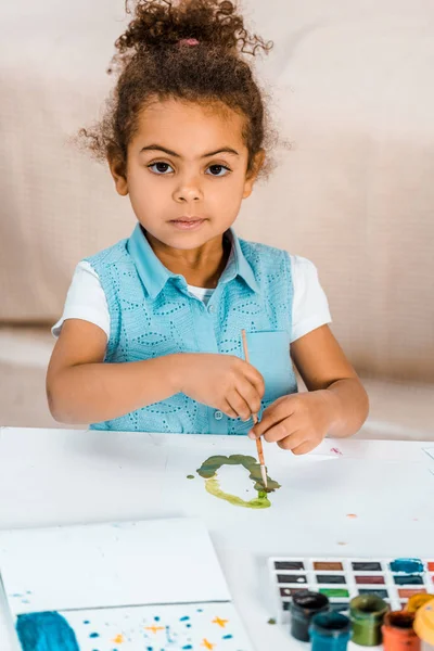 Adorable peinture d'enfant afro-américaine et regardant la caméra — Photo de stock