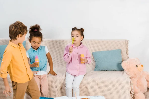 Красиві багатоетнічні діти грають з мильними бульбашками разом — стокове фото