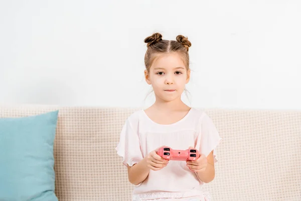 Adorabile bambino seduto sul divano e giocare con joystick rosa — Foto stock