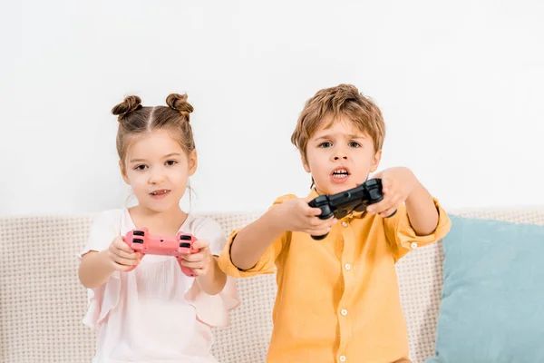 Adorables niños jugando con joysticks y mirando a la cámara - foto de stock