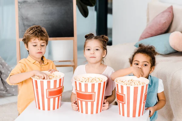 Очаровательные многонациональные дети едят попкорн из коробок — стоковое фото